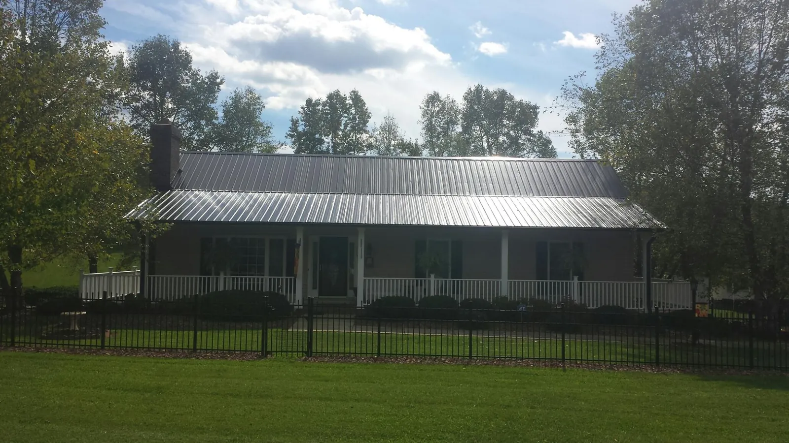 Gray metal roof on a brick ranch with a full width front porch — Gutter Guard Installation work by our crew in Nanticoke