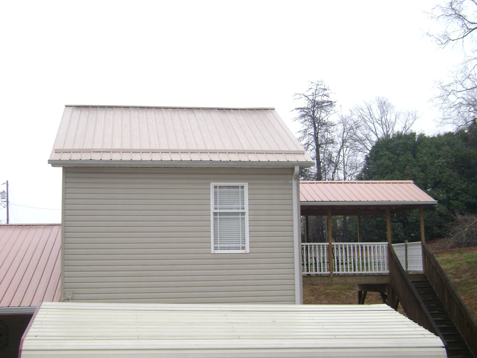 Tan metal roofs on a two story addition and attached porch, from a Roof Replacement job in Nanticoke