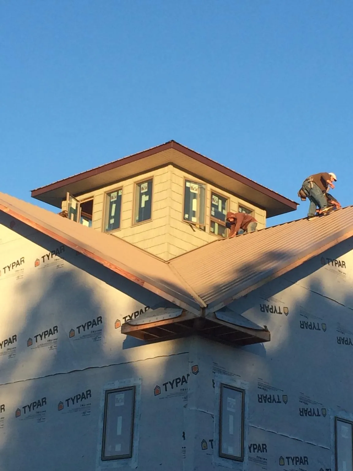 Roofers working around a rooftop cupola on a new metal roof at sunset — Roof Waterproofing in Nanticoke by Roofing Brothers